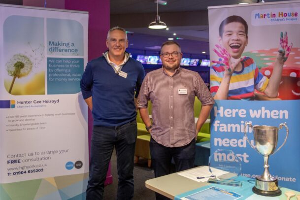 Two directors in front of HGH and Martin house banners.